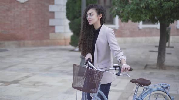 Slow Motion Of A Young Woman Walking At The Plaza With Bicycle alt