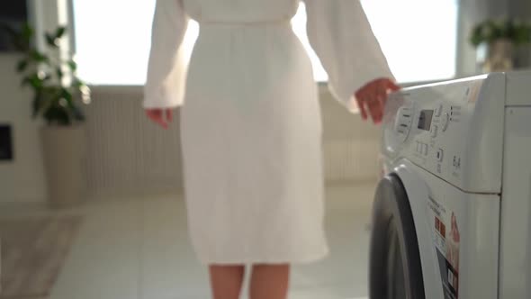 A Young Woman Turning on Washing Machine