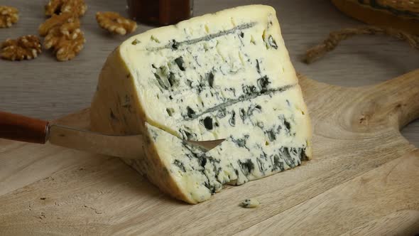 Cutting a piece of traditional French Bleu d'Auvergne cheese  alt