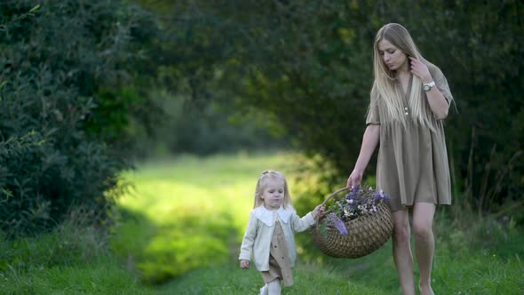 mum and daughter with wild flowers bouquet walking together outdoor enjoy beautiful field