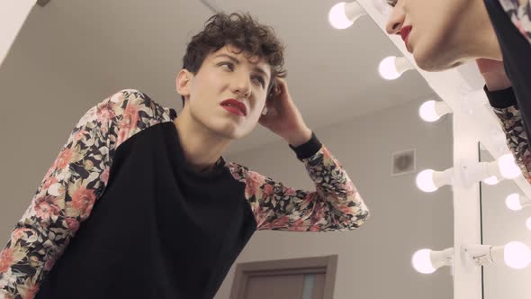 Transgender Man with Makeup Looks in the Mirror Doubtfully alt