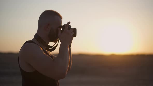 Young Man Using Camera and Taking Photographs Outdoors at Sunset