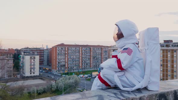 Astronaut sitting on wall looking over city