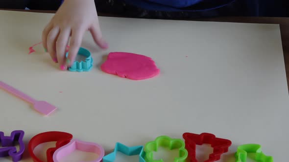 Hands of Little Girl 5 Years Old Playing Pink Play Dough with Plastic Molds