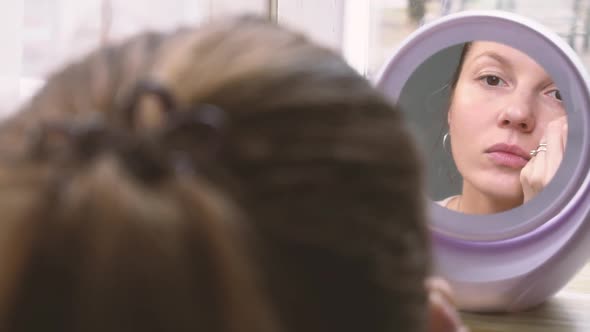 Woman Doing Makeup at Home and Looking Into the Mirror