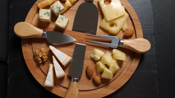 Sliced Cheese, Nuts and Knife on Wooden Platter. Rotating alt