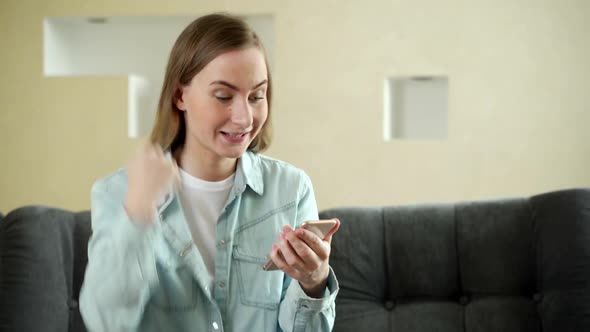 Happy Woman Holding Smartphone and Making Successful Deal While Working From Home. Woman Winning Big alt