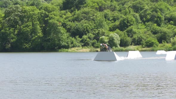 Young Man Jumping on the Ramp with His Wakeboard While Freeriding on a Lake alt