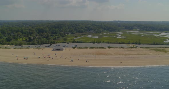 Aerial Panning Shot of a Sandy Beach Shore Near a Forest on a Sunny Day alt