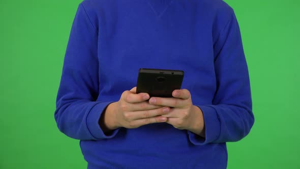 A Young Boy Works on a Smartphone - Front Closeup - Green Screen Studio alt