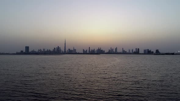 Aerial view at water level of Dubai skyscrapers and bay at sunset, UAE. alt