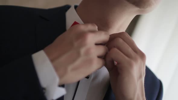 Man Adjusts Red Bow Tie Closeup