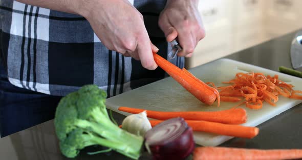 Man peeling carrot in kitchen at home 4k