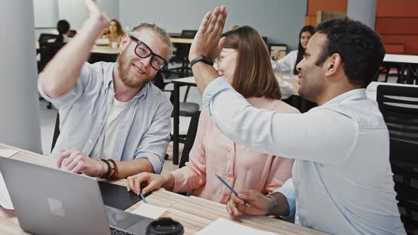 Young Multiracial Diverse Colleagues Rejoicing That They Have Developed New Business Plan Sitting at alt