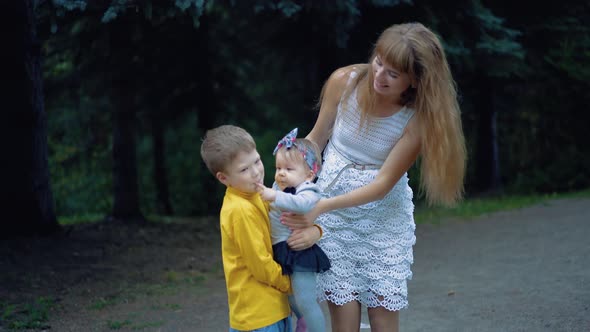 Young Mother and Her Two Sons Play with the Baby alt