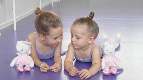 Two Little Ballerinas Lying on the Floor at Ballet School Resting After Practicing