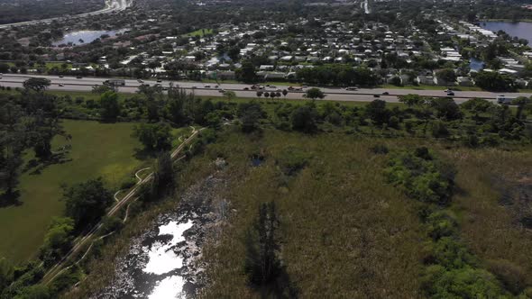 Aerial doing a partial orbital of a florida highway with a neighborhood in the background alt