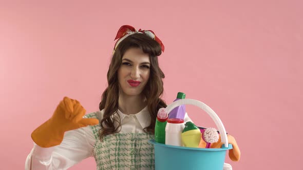 A Woman Holds a Bucket of Cleaning Tools and Shows a Thumbsdown Gesture