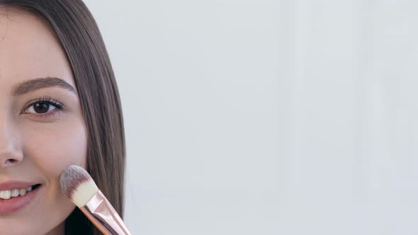 Female Face During Using Make Up Brush for Applying Blush alt