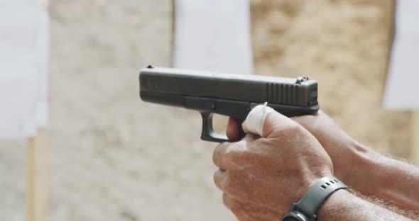 Slow motion close up shot of a man shooting a hand gun while moving backwards alt