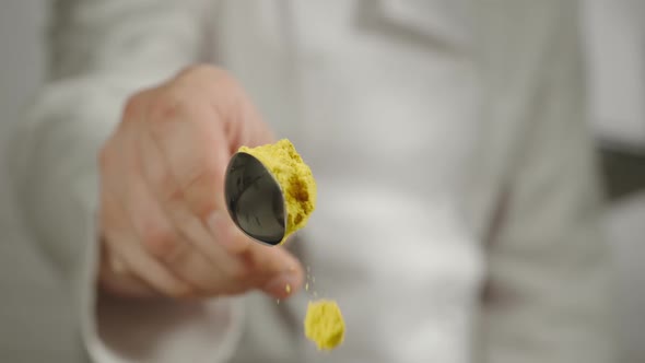 Chef Sprinkles Yellow Turmeric Powder From A Spoon
