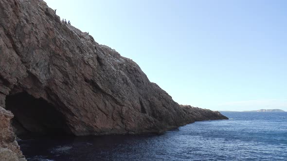 Large rocky cave in a cliff by the ocean. Stunning sea cave in Ibiza. alt