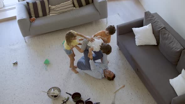 Caucasian Man Lying on Back and Playing with Kids in Living Room
