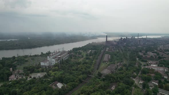 Aerial View of the City Near a Large Industrial Plant with Pipes and Smoke alt
