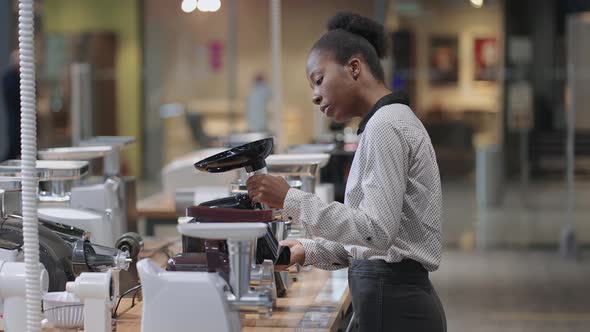 Afroamerican Woman is Viewing Electric Meat Grinder in Shop Young Housewife Wants to Buy Home alt