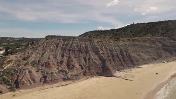 Crane up over Big cliff slope bordering Praia da Luz flank, Algarve - Aerial alt