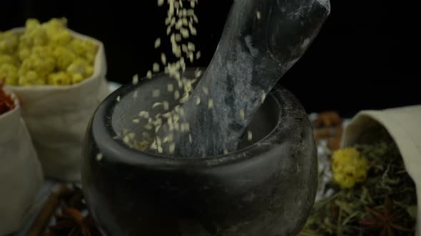 Sesame falling into the granite mortar with pestle alt