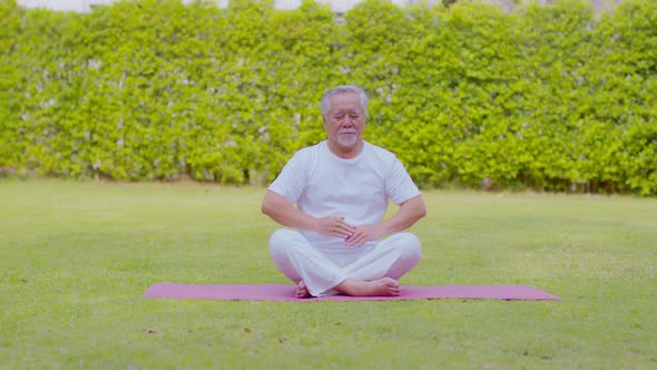 Calm of Healthy Senior Asian man wearing white shirt and pant doing Tai Chi Chuan for Meditation alt