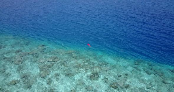 Luxury flying travel shot of a paradise sunny white sand beach and blue water background  alt