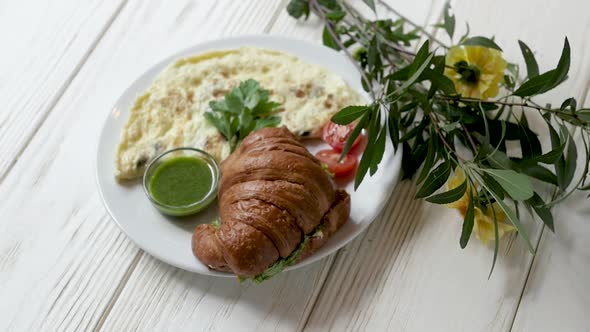 Breakfast with Fresh Croissant and Omelet. Breakfast Stands on a Wooden White Background with alt