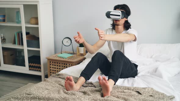 Happy Guy in Pajamas Using Vr Glasses in Bed at Home Racing Having Fun alt
