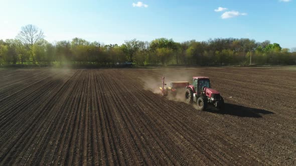 Aerial View of Tractor Working in the Dust Field with a Modern Sowing Seeds Machine in a Newly