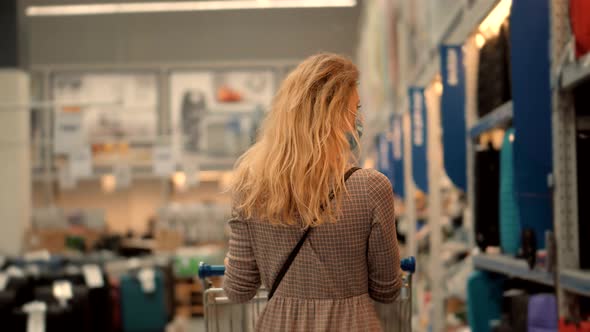 Woman Shopping And Walks Through Supermarket With Basket. Girl In Face Mask Shopping In Market. alt