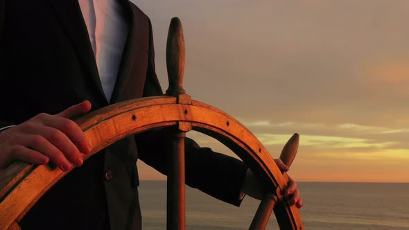 Businessman holding ship rudder and steers