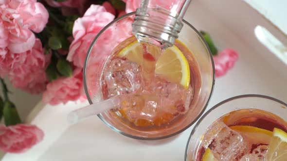 Top View of Strawberry Carbonated Drink Lemonade is Poured Into Glass with Ice and Lemon