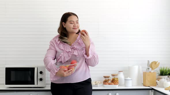 Happy Young woman eating apple in the kitchen