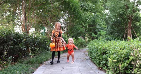 Cute Little Caucasian Kids with Blonde Hair Seven Years Old in Costume of Witch with Hat and Baby alt