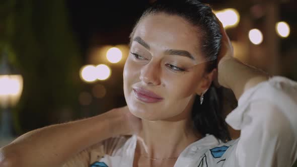 Portrait of Thoughtful Wet Woman Caresses Her Hair at Camera in Deep Evening