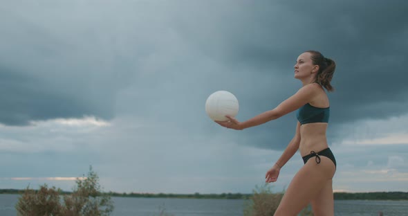 Young Sportswoman Dressed Bikini Is Playing Beach Volleyball, Medium Shot Against Picturesque Cloudy alt