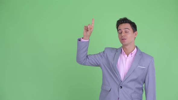 Happy Young Handsome Businessman Talking and Pointing Up alt