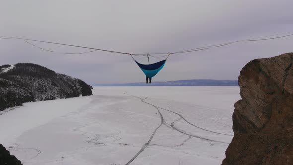 Man Hanging in Hammock Above By Ice of Frozen Lake Baikal