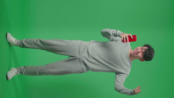 Full Body Of Asian Man Celebrating While Using Mobile Phone In The Green Screen Studio alt