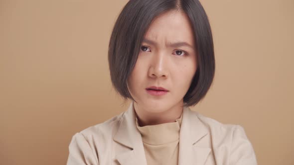 Close up shot of Asian business woman angry and looking at camera isolated over beige background.