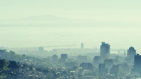 General view of cityscape with multiple modern buildings and shore covered in smog alt