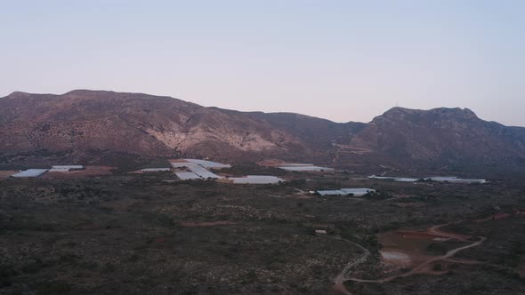 Aerial view of big Industrial greenhouses near mountain. Industrial agriculture in Greece alt