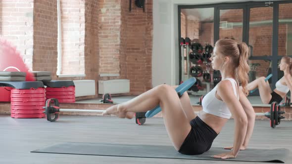 Fit Athletic Woman Doing Fitness Training with Pilates Ring Between Knees at Gym